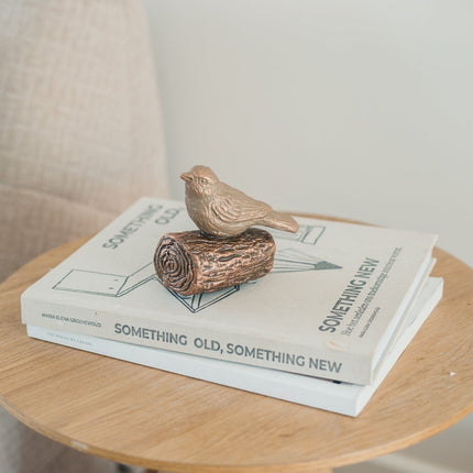 De urn is gemaakt van keramiek en heeft de kleur brons. De urn is een vogeltje die staat op een kleine boomstronk. De urn staat gestationeerd op twee boeken die liggen op een klein rond houten tafeltje.